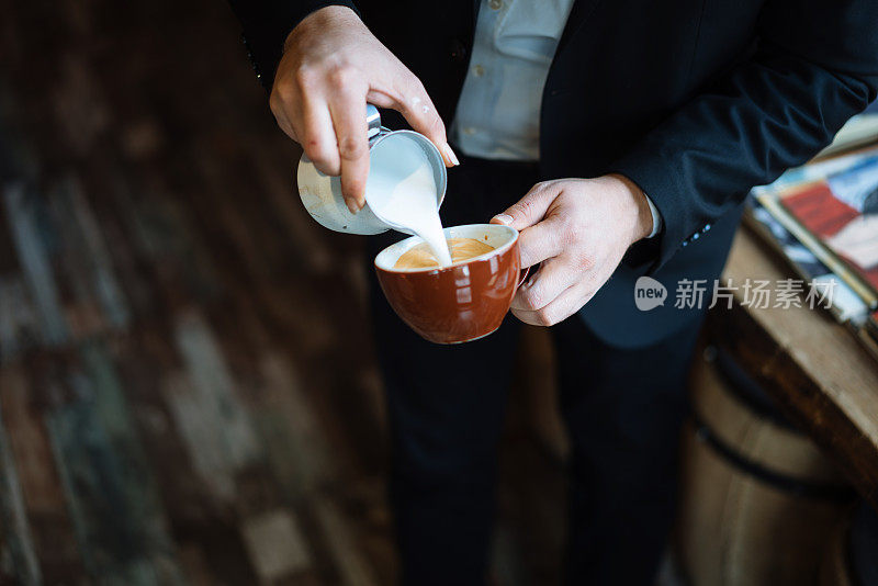 咖啡师拿着咖啡杯，制作拉花咖啡