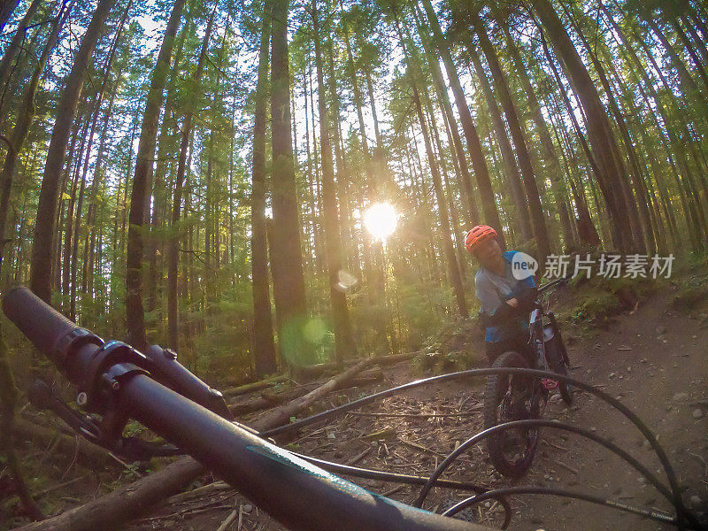 POV，山地自行车手在阳光照耀的森林小径休息，加拿大