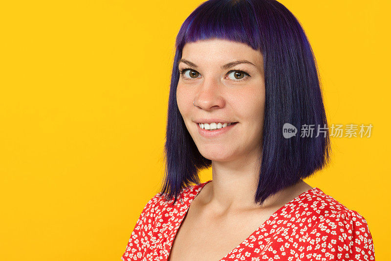 一个年轻女子在工作室里的肖像，穿着红色的裙子，紫色的头发在黄色的背景