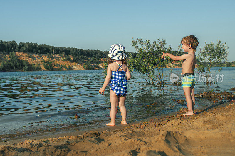 夏天，小男孩和小女孩在湖边的沙滩上玩耍