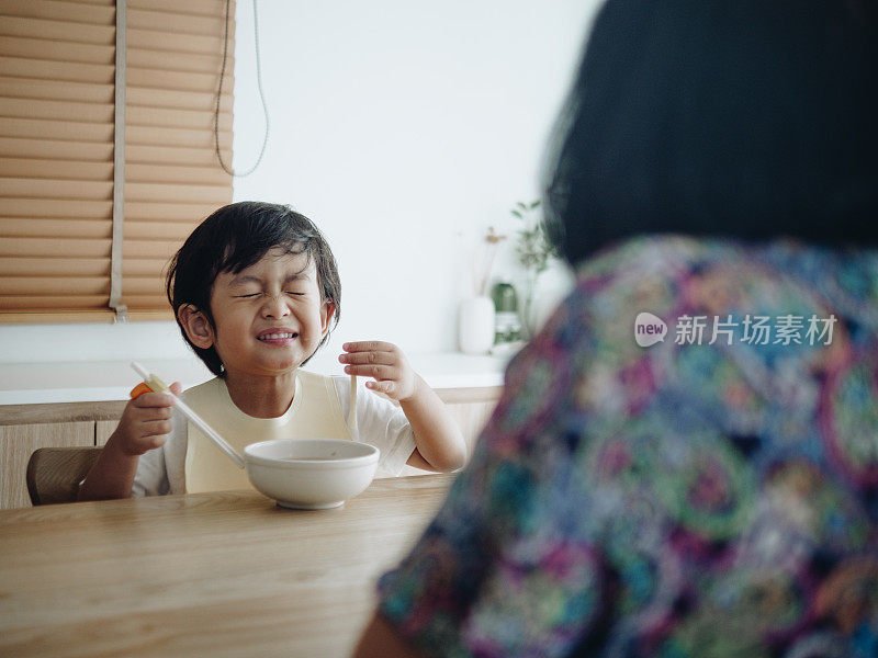 微笑的小男孩在高椅子上吃