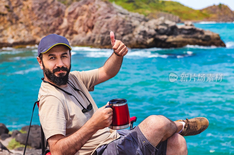 一个男人坐在海滩上的露营椅上