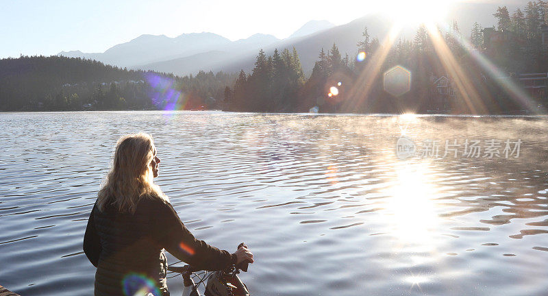 日出时分，女人沿着湖边的码头骑自行车
