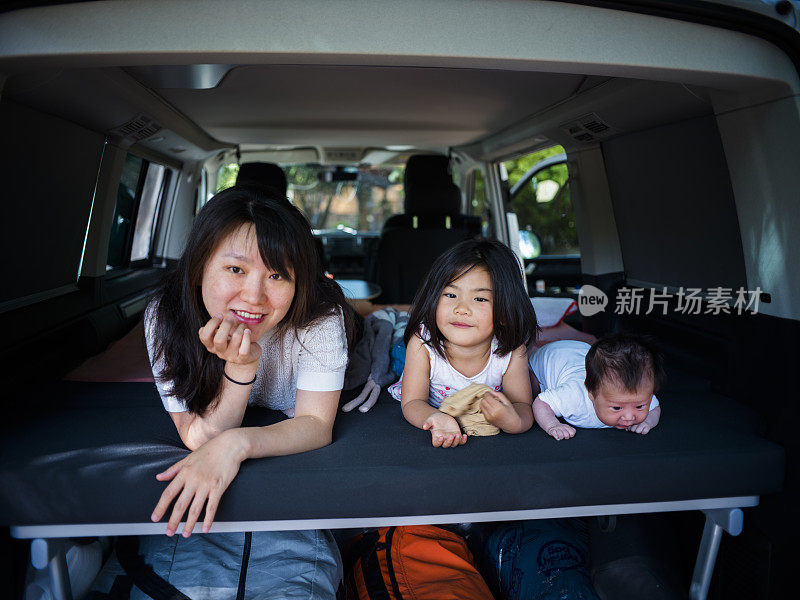 一个女人和两个小女孩躺在森林里的野营车里