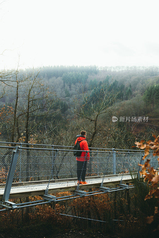 一个背包客在吊桥上散步，欣赏德国自然美景