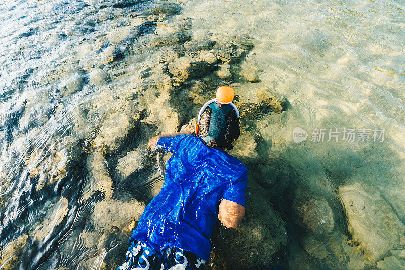 男孩浮潜在海岸线的海洋