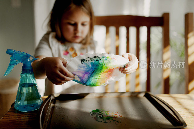 小女孩用咖啡滤纸把多余的染料滴到烤盘上