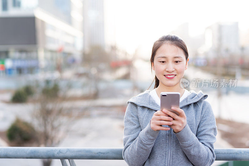 亚洲年轻女子在城市公共广场使用手机