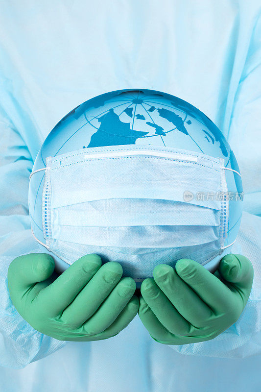 大流行概念-医生的手在手套拿着地球在一个医疗口罩