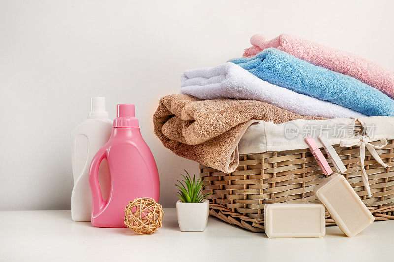 柳条洗衣篮里有毛巾，洗涤剂，肥皂和竹球在白色的背景
