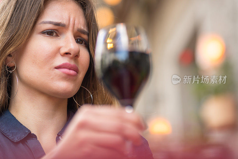 一个女人厌恶地看着一杯红酒