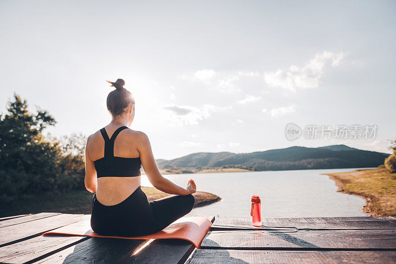 一个白人女孩在大自然中练习瑜伽，早上在山上的湖边