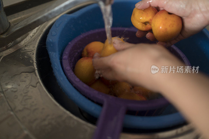 女人的手在水里洗两个杏子