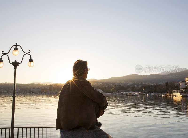 日落时分，在湖边散步时，太阳从一名男子的肩头升起