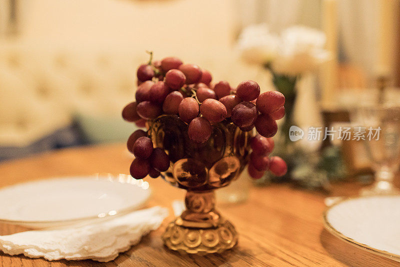 在舒适的感恩节餐桌装饰，深红色葡萄在一个复古杯