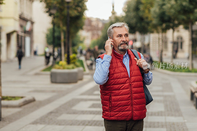一个老人在城市里边走边讲电话