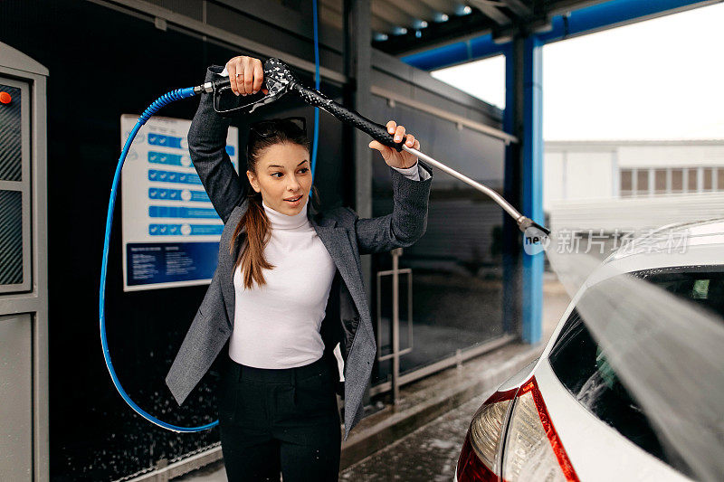 一个女人用泡沫水枪清洗她的车