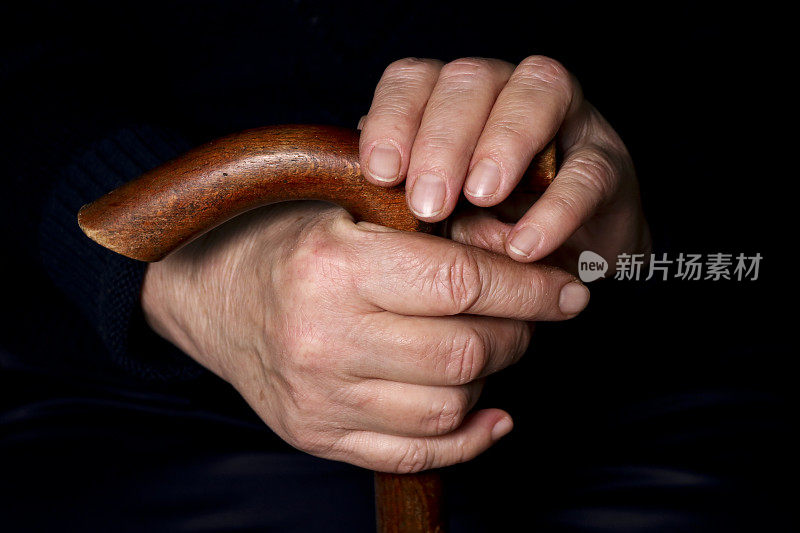 老妇人的手握着一根t形手柄的老拐杖。老年、孤独、关怀、照顾老人的观念。