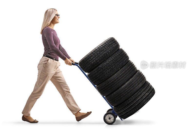年轻女子推着一辆装满汽车轮胎的手推车