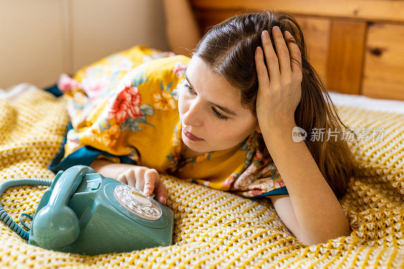 在电话旁等待她的情人的电话，一个金发的年轻女子在床上坐在电话的深夜