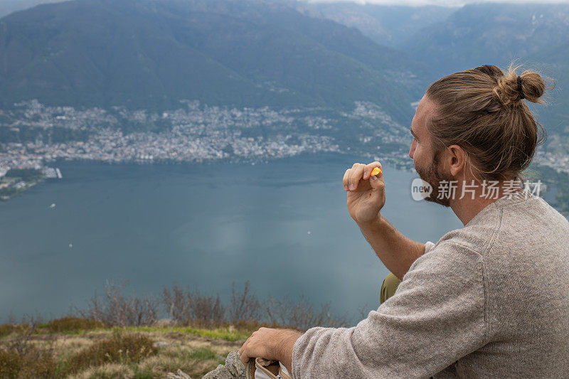 男性徒步者在山顶享受食物，吃零食