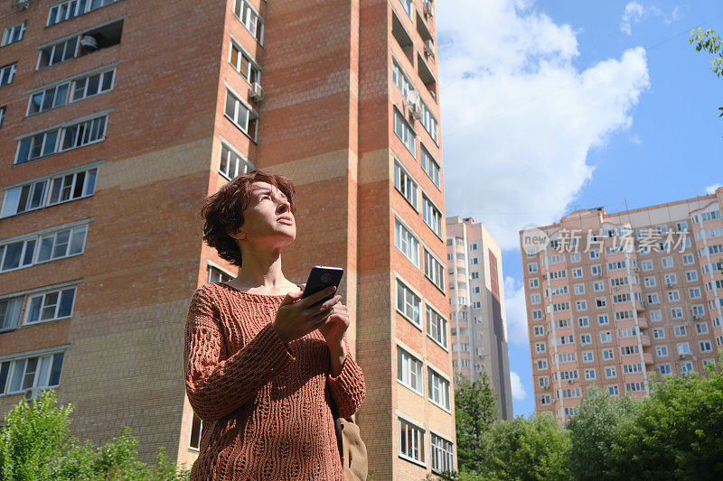 成熟的女人正在寻找城市里的地址。她正在用智能手机上的地图