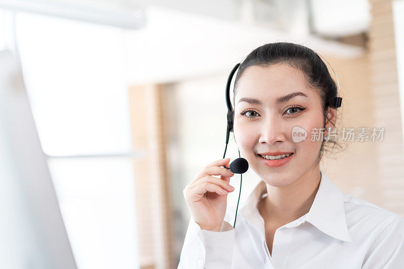 微笑的亚洲呼叫中心的女人。女客服接线员，头戴耳机在办公室工作。呼叫中心和客户服务的耳机概念