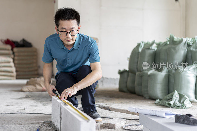 亚洲男性工程师与卷尺工作在翻新工地