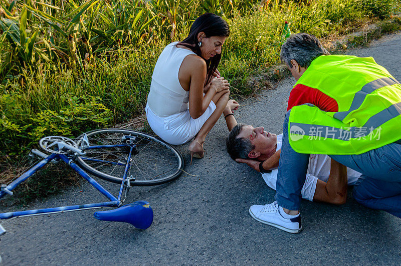 一个骑自行车的人在路上发生了可怕的车祸，当时一男一女正试图帮助他。