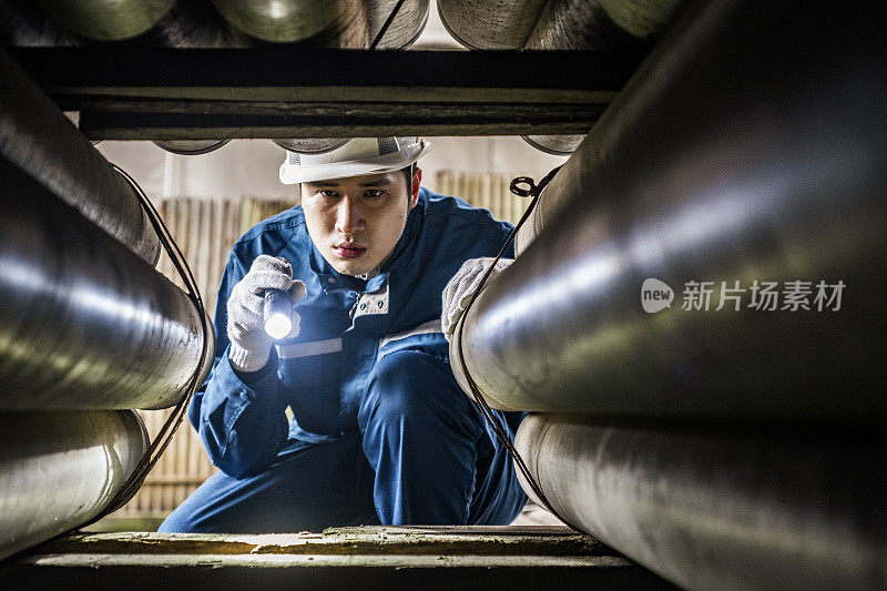 蓝领工人用手电筒检查管道