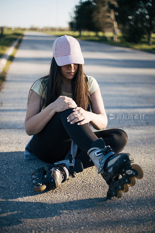 女孩戴着帽子骑旱冰鞋摔倒了