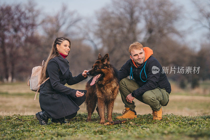 一对恩爱的夫妇和一只德国牧羊犬在公园里