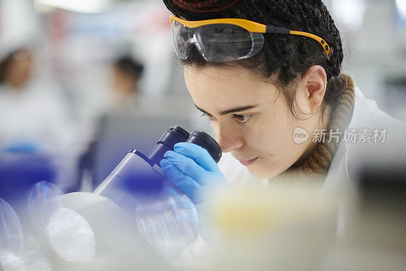 年轻女性生物化学家用显微镜