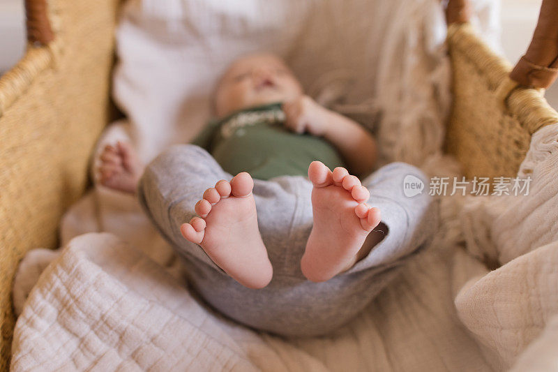 一个9周大的男婴的12个脚趾躺在一个舒适的奶油棉毯子在海草摩西篮子