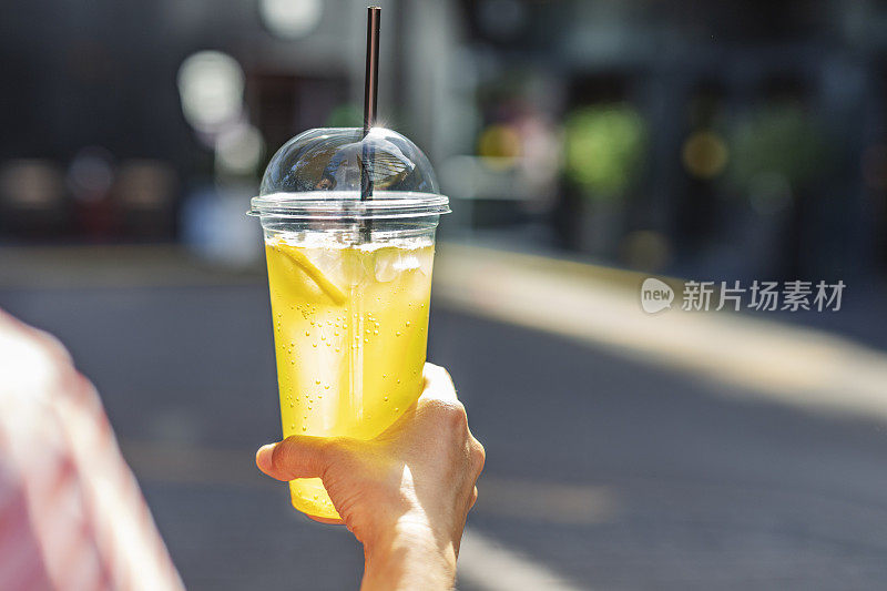 用塑料杯盛着柠檬水的女人的手