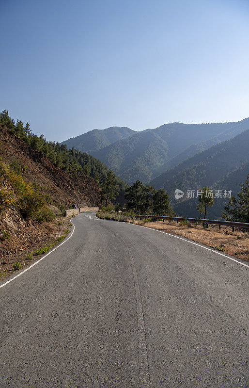 道路环抱着平缓蜿蜒的山坡，穿越陡峭的火山地形，与远处朦胧的山峦遥相望