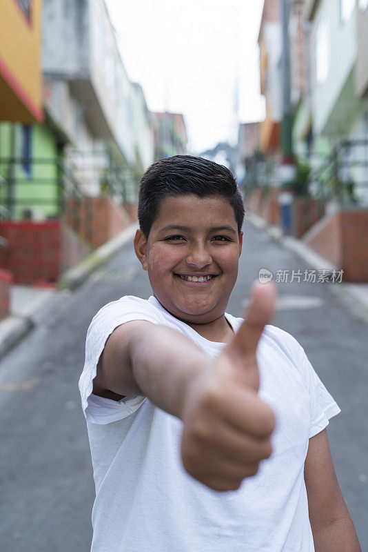一个平均年龄为13岁的拉丁男孩在街上微笑着看着描绘他的摄像机