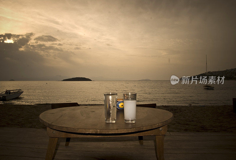 在海滩上的木桌上，除了美丽的海景，还有烤肉或茴香酒