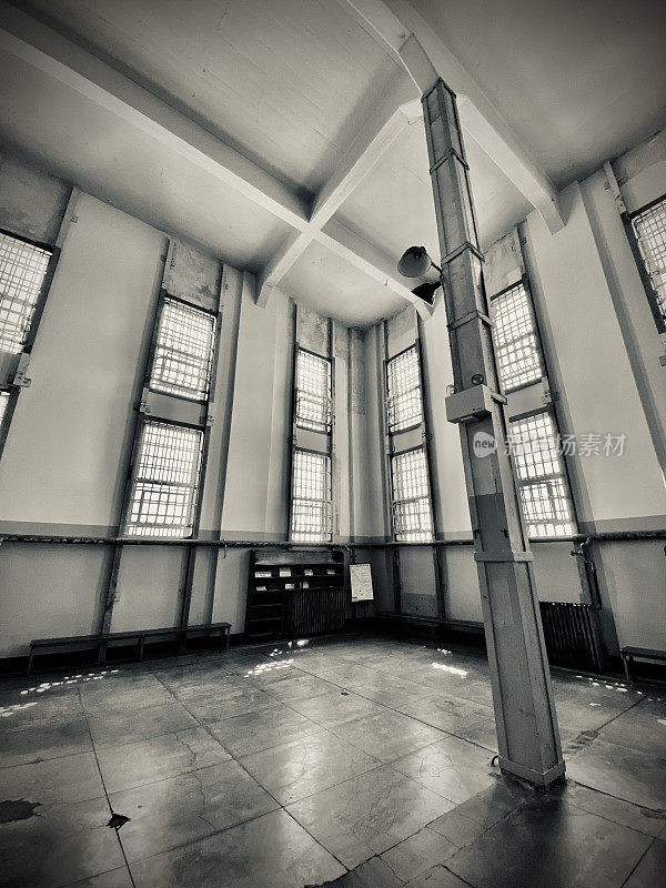 站在恶魔岛联邦监狱内与监狱图书馆相邻的空旷走廊上。(黑白)