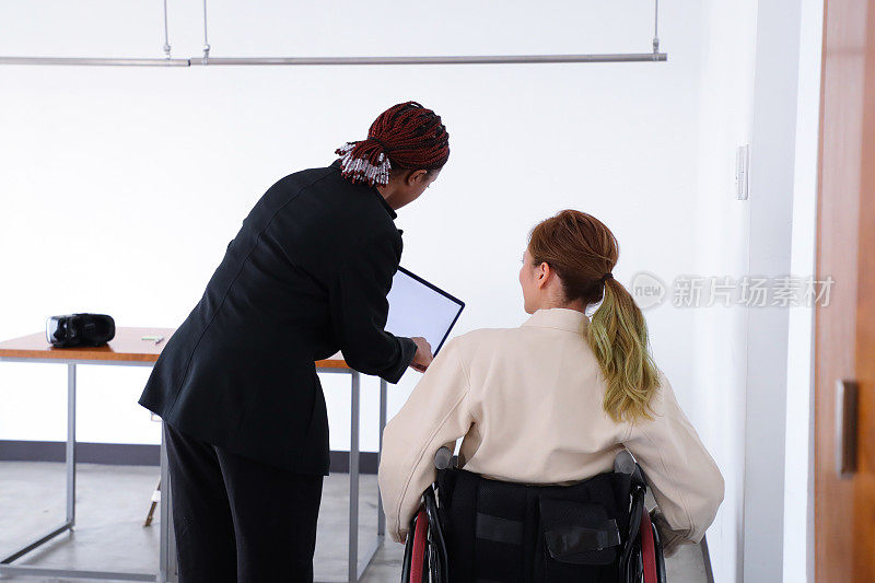 坐轮椅的女商人在多元化的办公环境中工作
