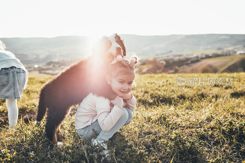 微笑的小女孩在花园里和伯恩山狗玩耍