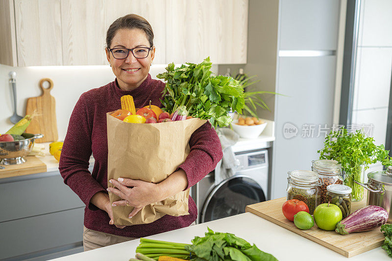 女人拿着装满水果和蔬菜的纸质购物袋