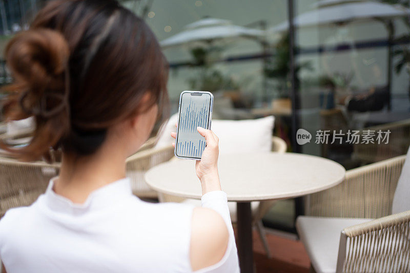 年轻的亚洲女性在智能手机上观看图表
