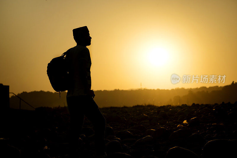 一个年轻人站在夕阳下的剪影。