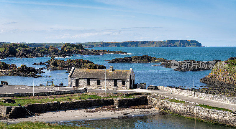 夏天，北爱尔兰巴林托伊港海岸线上的石头房子
