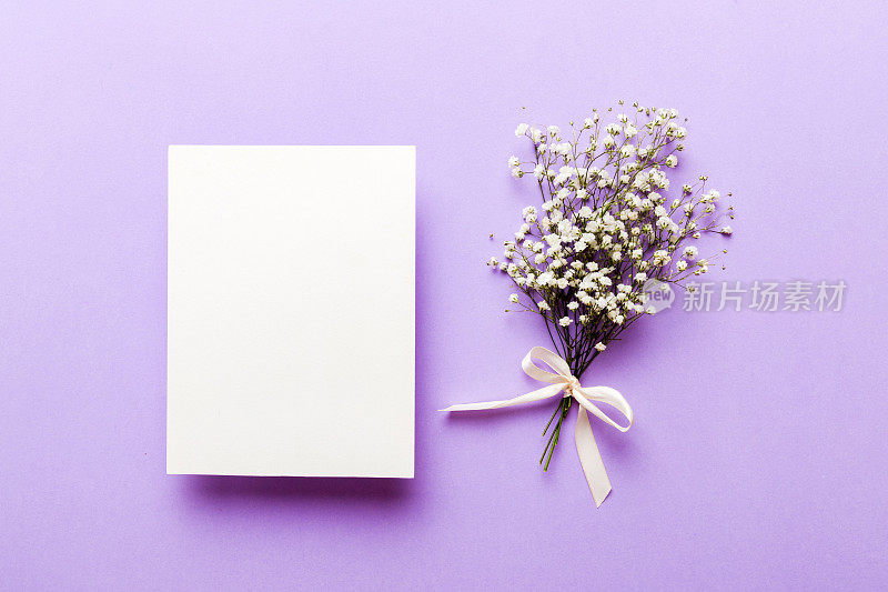 婚礼模型与白色的纸清单和鲜花石膏在彩色的桌面视图平躺。空白的贺卡和信封。漂亮的花卉图案。平铺式