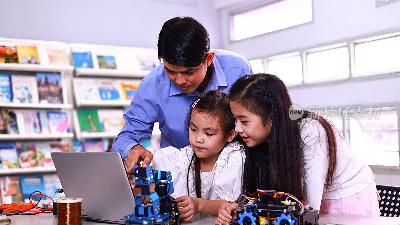在stem机器人课上，年轻的女学生们正在制作一个机器人，她们和男老师一起用电线套件工作。孩子们的发明和创造力