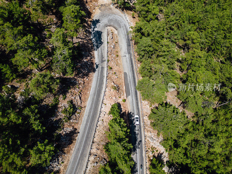 在森林山区的道路上行驶的车辆用无人机拍摄沥青弯道