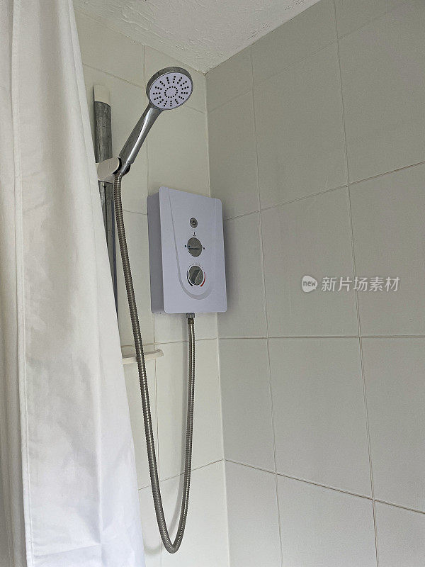 近景现代，壁挂式，浴帘后的电动淋浴单元，镀铬防扭结软管和支架立管，白色瓷砖墙