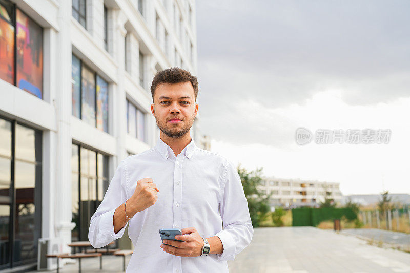 一个年轻人在户外拿着手机，另一只手举在空中